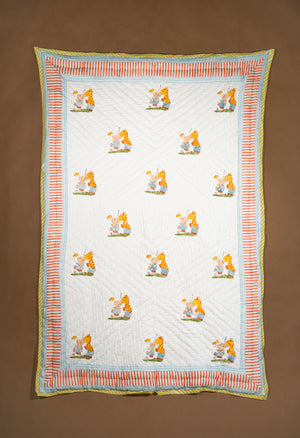A handmade quilted baby blanket featuring a white center with a repeating pattern of cartoon bears and giraffes, surrounded by a striped border in orange, light blue, and yellow, laid flat on a brown background.