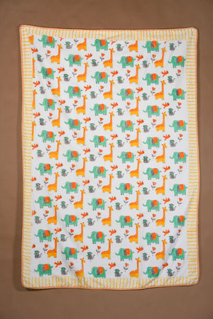 A square baby blanket with a white background featuring a repeating pattern of orange giraffes, green elephants, and gray acacia trees, finished with a yellow and orange zigzag border, shown flat against a brown background.